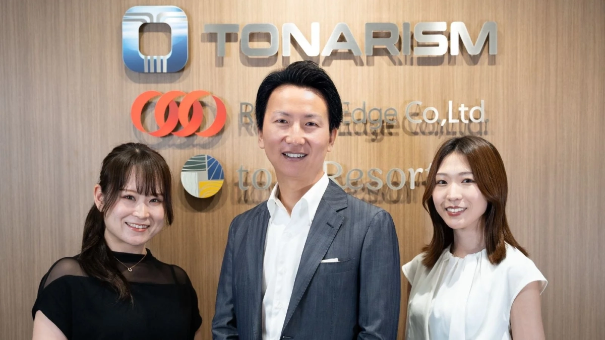 笑顔の男女3人が並んで立つTONARISM社のビジネスシーン