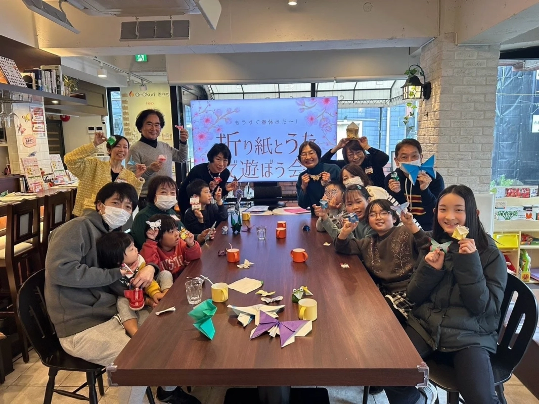 子供から大人まで、多くの人々が笑顔で折り紙を楽しむイベントの様子