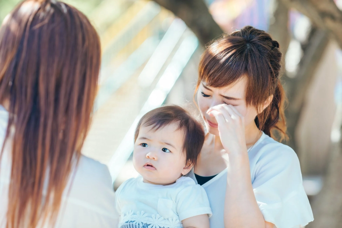 赤ちゃんを抱っこして涙を拭う女性
