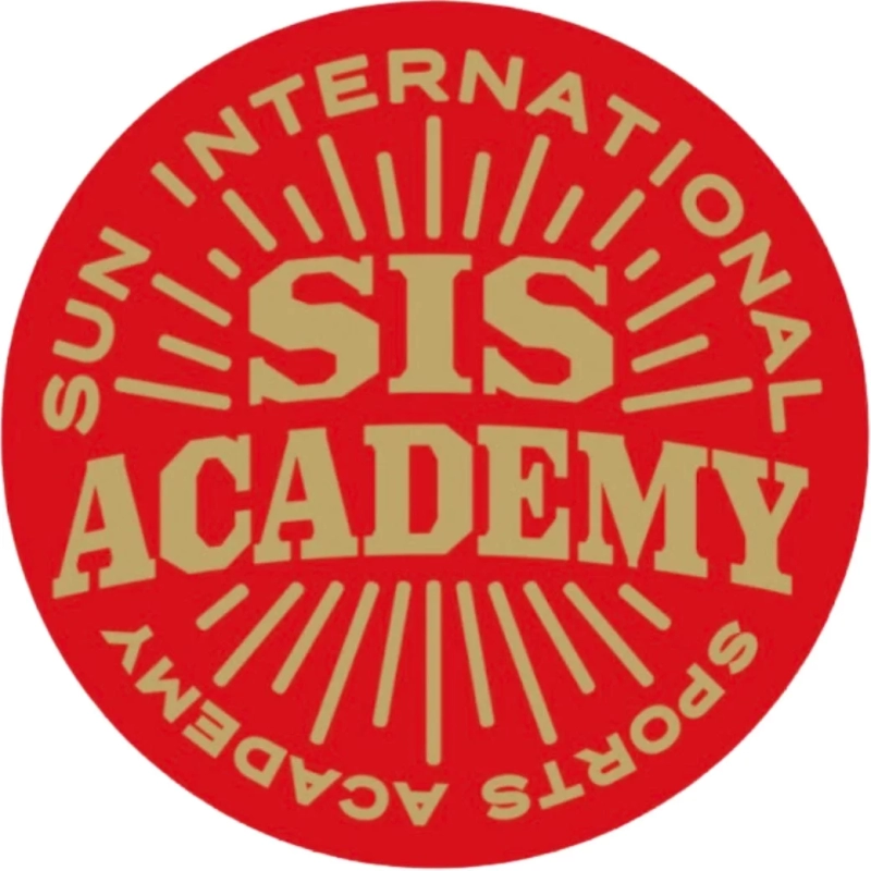 「SUN INTERNATIONAL SIS SPORTS ACADEMY」と書かれた円形のロゴマークです。赤色の背景に金色の文字と放射状のラインがデザインされており、スポーツ関連のアカデミーを示唆しています。