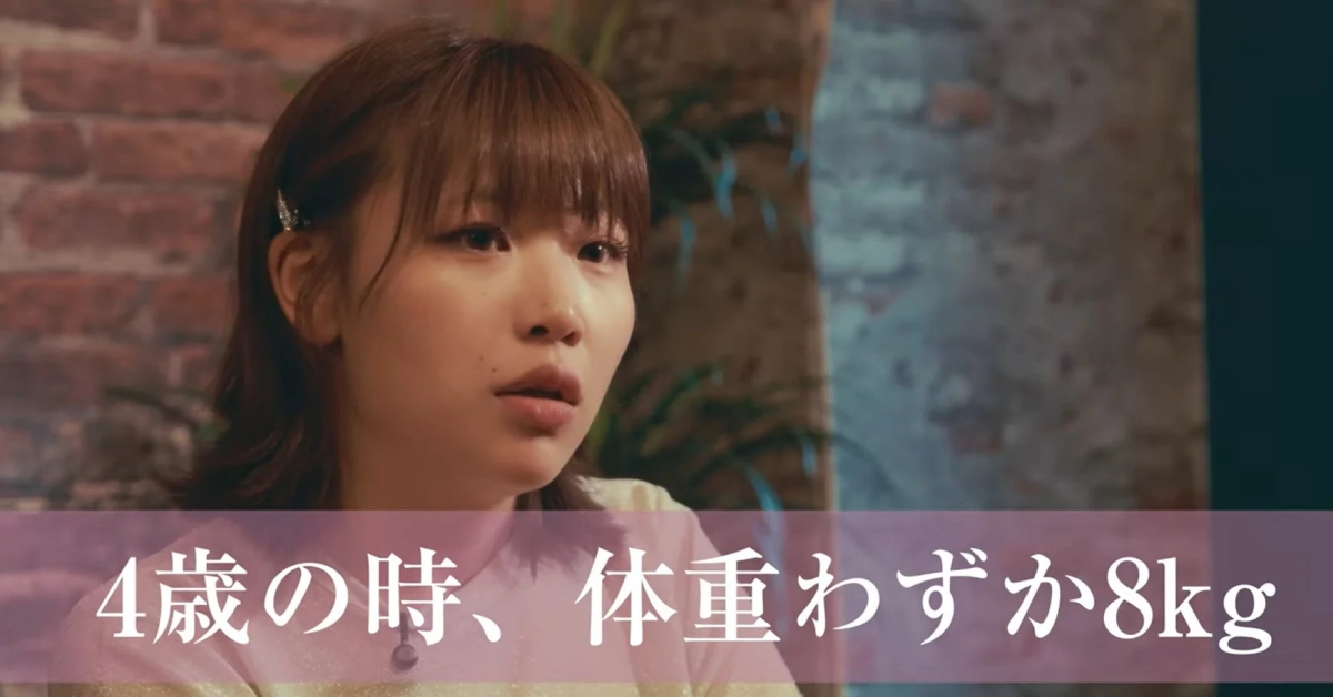 レンガ壁を背景に、何かを考え込むような表情の女性