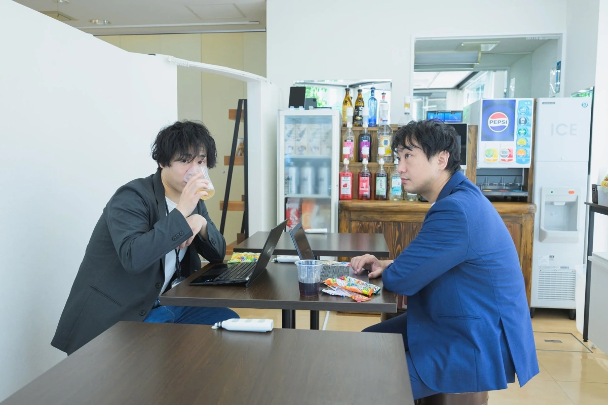 ノートパソコンを挟んで会話する男性たち