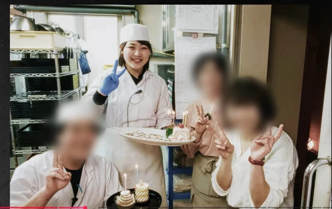 厨房で「Happy Birthday」と書かれたケーキを持つ女性