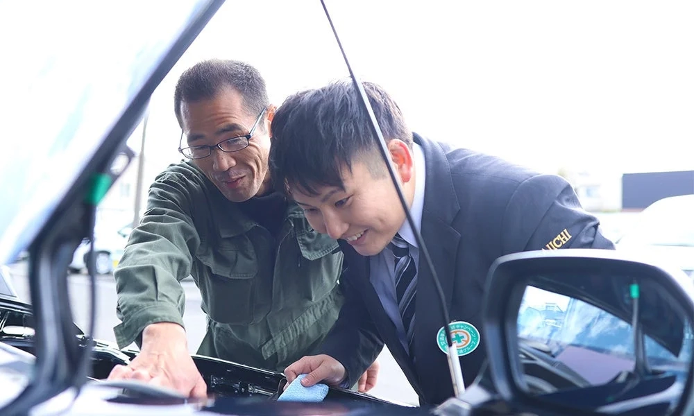 車のボンネットを開けて点検・清掃しているスーツ姿の男性