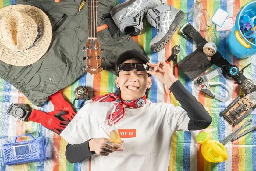 カラフルなシートに寝そべる笑顔の男性。楽しげなライフスタイルを表現