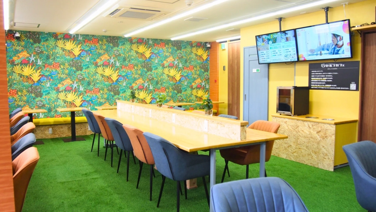 人工芝の床と鮮やかなジャングル柄の壁紙が特徴的なセルフカフェの内装